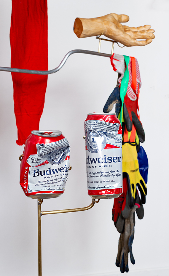 Detail of sculpture, featuring crumpled Budweiser cans, cast hand and gloves